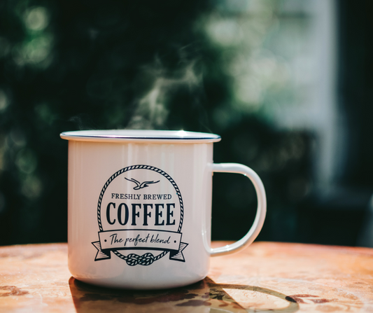 What is white coffee? a close up of a white enamel cup holding a steaming drink on a wooden table