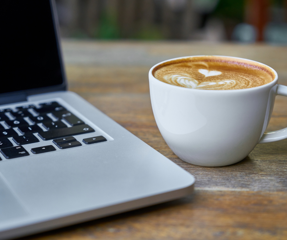 Does Coffee Actually Increase Productivity? A coffee on a wooden table next to an open laptop.