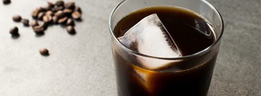 Close up of a cold brew coffee with an ice cube in a clear glass